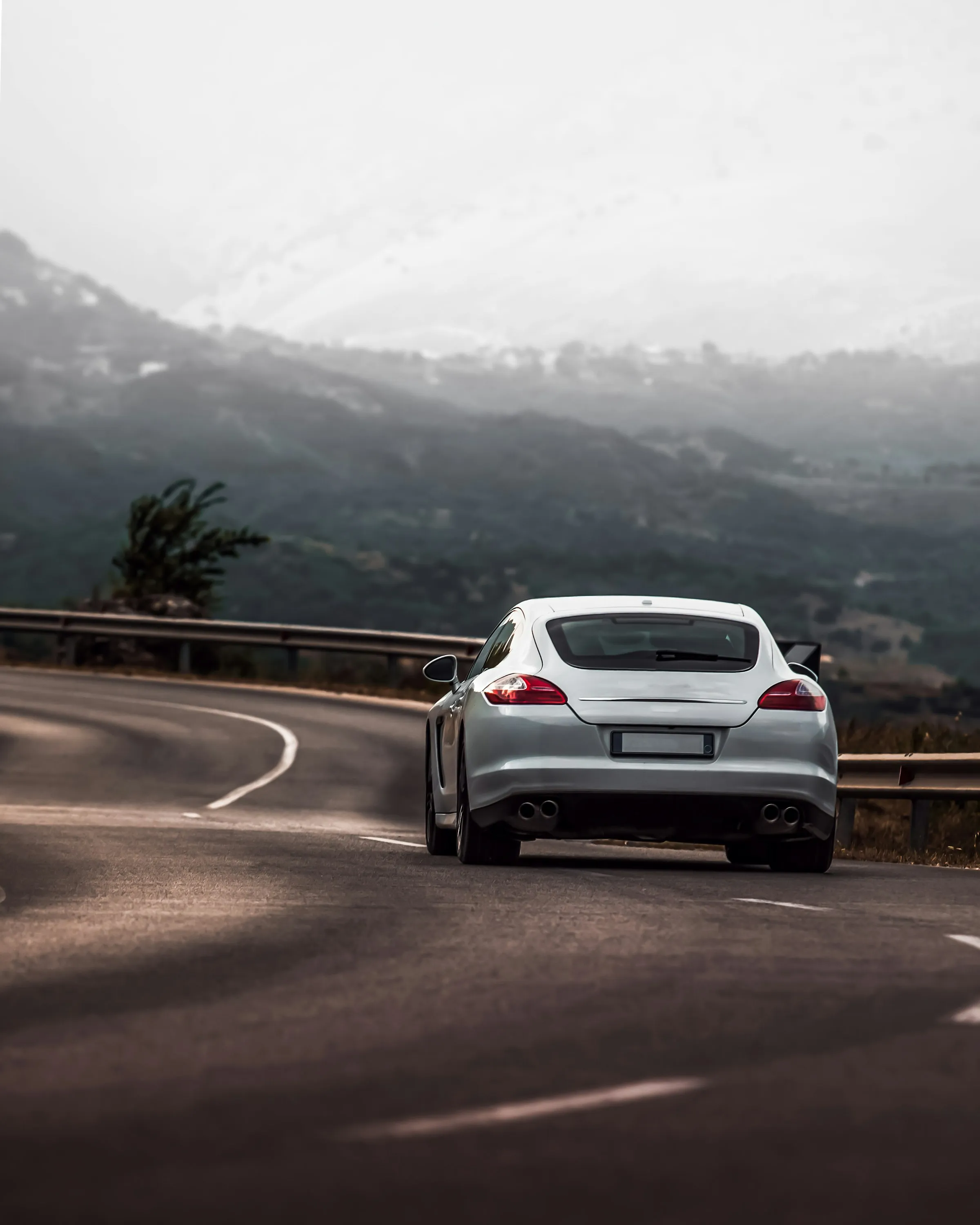 Coche blanco en una carretera de montaña con niebla